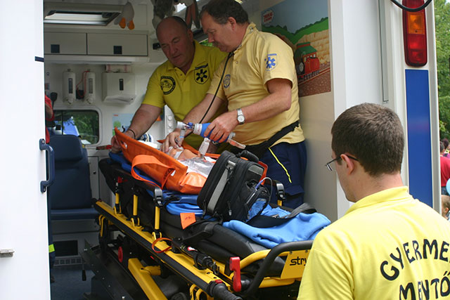 A mentők elhelyezik a sérült gyereket a Gyermekrohamkocsiban
