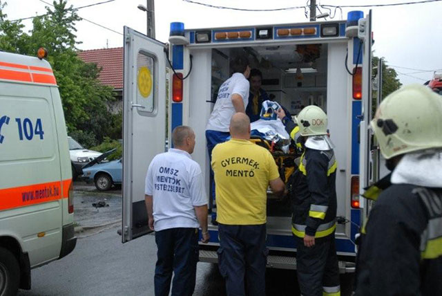A mentők beemelik a hordágyat a Gyermekrohamkocsiba